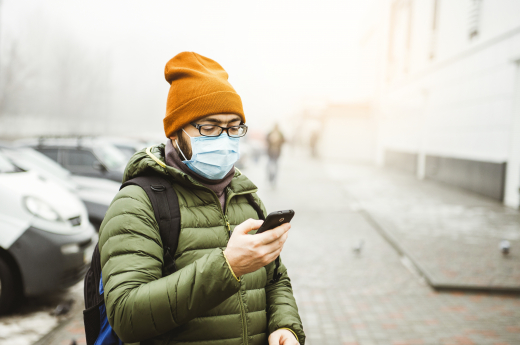 A person wearing face mask, checking mobile phone