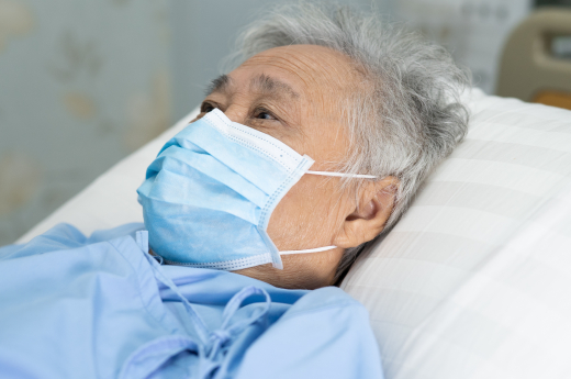 elderly person wearing surgical mask , lying on bed