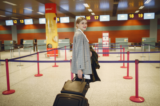 Cheerful female passenger walking with luggage in an airport hall